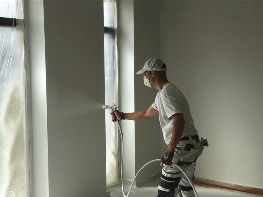 Schilder spuit een binnenwand in een nieuwbouwwoning