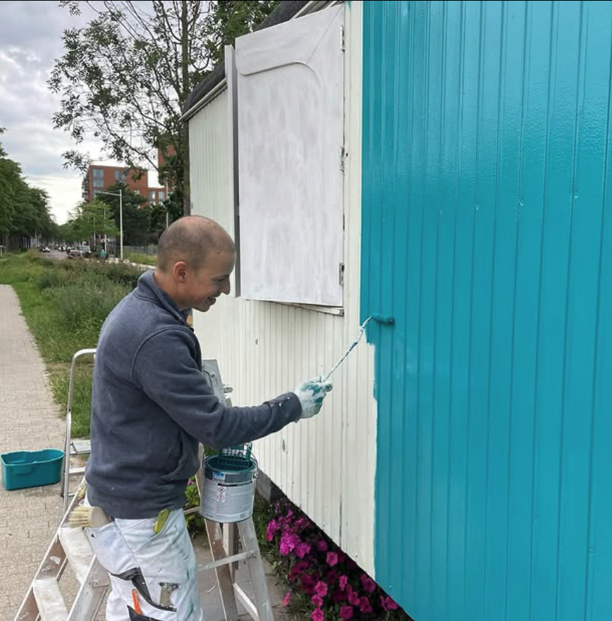 Schilder werkt buitenwerk bij op een houten gevel